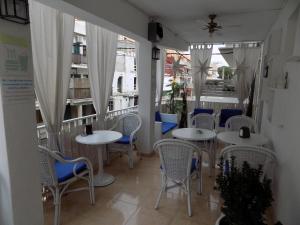 um restaurante com mesas e cadeiras brancas e janelas em Hostal Villa Maruja em El Arenal
