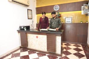 un hombre y una mujer parados en un mostrador en Hotel Panna Paradise, en Agra