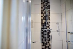 a shower with a black and white tiled wall at Hotel Restaurant BEAU in Bergeijk