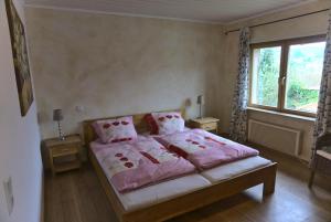 a bedroom with a bed with pink sheets and a window at Ferienwohnung im Haus Waldblick in Nonnweiler