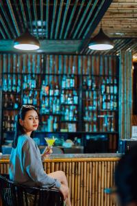 uma mulher sentada num bar com uma bebida em Chay Lap Farmstay Phong Nha em Ðá Lòn