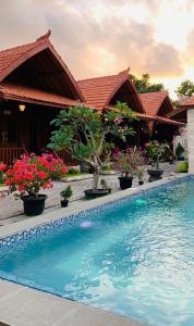 a swimming pool in front of a house with flowers at Uli Wood Villa, Jimbaran BALI - near GWK in Jimbaran