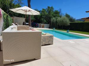 une chaise en osier et un parasol à côté d'une piscine dans l'établissement Casa Il Pino, à Camaiore