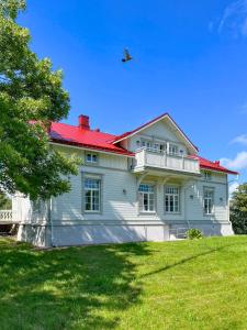 een vogel die over een wit huis vliegt met een rood dak bij Strandnäs Gård in Mariehamn