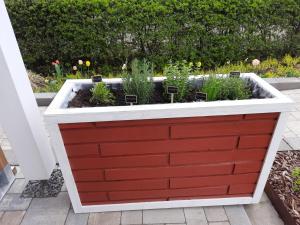 um jardim de ervas numa caixa de plantação vermelha e branca em Ferienhaus Deine Zeit mit SAUNA und WALLBOX em Nettersheim