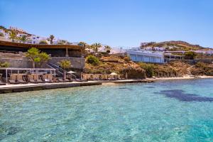 einen Wasserkörper mit Stühlen und einem Strand in der Unterkunft Saint John Hotel Villas & Spa in Agios Ioannis Mykonos