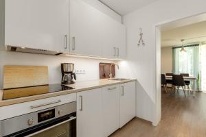 eine Küche mit weißen Schränken und einer Arbeitsplatte in der Unterkunft Sellinkoje in Residenz Waldidyll in Ostseebad Sellin + 22 Fotos