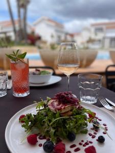 a table with a plate of food and a glass of wine at Nuramar Resort & Villas in Cala en Bosc
