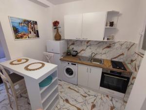 een keuken met witte kasten, een tafel en een wastafel bij Melograno in Tivat +1 foto
