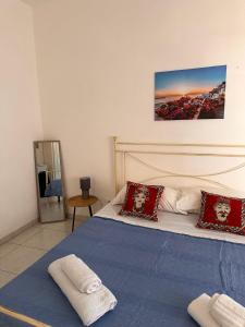 a bedroom with a bed with blue sheets and red pillows at A Due Passi dal Centro in Favignana