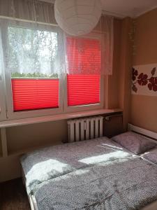 a bedroom with two windows with red blinds at Atrakcyjne Matejki in Świnoujście