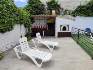 2 sillas blancas en un patio con chimenea en Casa Villazo I, en Almáchar