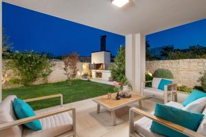 un patio con sillas, mesa y chimenea en Luxury apartment Hyperion with private pool and garden, en Murter