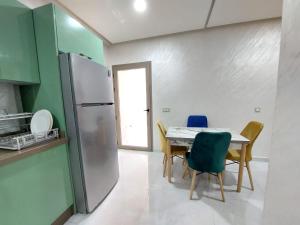Il comprend une cuisine équipée d'une table, de chaises et d'un réfrigérateur. dans l'établissement Très bel appart climatisé proche de la plage, à Agadir
