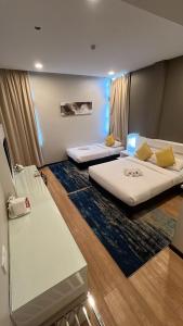 a hotel room with two beds and a couch at Lovita Hotel Kuantan in Kuantan