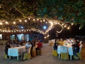 eine Gruppe von Personen, die an Tischen unter Lichtern sitzen in der Unterkunft New Belitung Holiday Resort in Pasarbaru