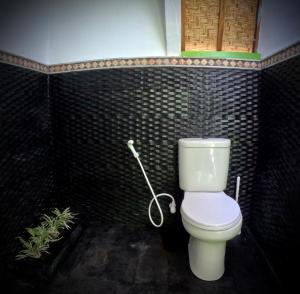 a bathroom with a toilet in a black tiled wall at Kaktus bungalow 1 in Gili Air