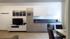 a kitchen with white cabinets and a table with chairs at Relais Gentilini in Malè