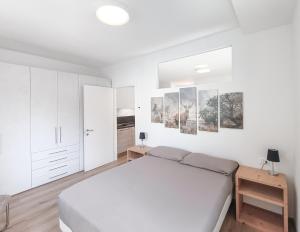 biała sypialnia z łóżkiem i zdjęciami na ścianie w obiekcie Relais Gentilini w mieście Malè