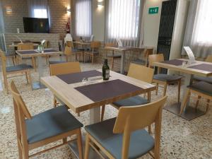 a dining room with tables and chairs and a bottle of wine at Hostal Moreno in Silla