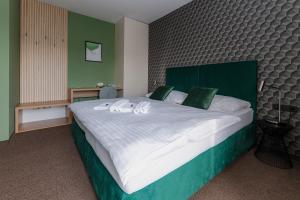 a bedroom with a large bed with a green headboard at Penzion Tofi in Nitra