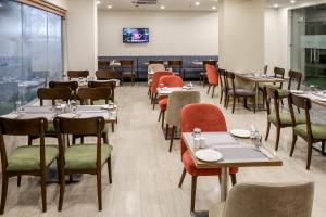 a restaurant with tables and chairs and a large window at Starlit Suites Newtown Kolkata in kolkata