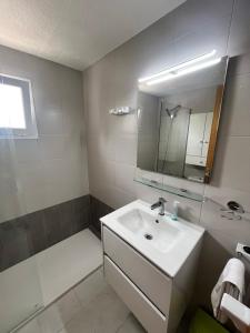 un bagno con lavandino, doccia e specchio di Portobello Verena a Port de Pollença Altre 18 foto