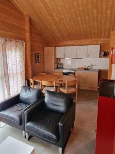 uma cozinha e sala de jantar com uma mesa e mobiliário de couro em Chalet Blockhaus auf Camping - b48513 em Oberwil