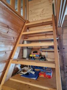 uma escada numa pequena casa com uma pilha de madeira em Chalet Blockhaus auf Camping - b48513 em Oberwil