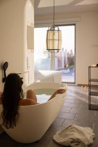una donna seduta in una vasca da bagno in una stanza di Thalasses ad Adelianos Kampos
