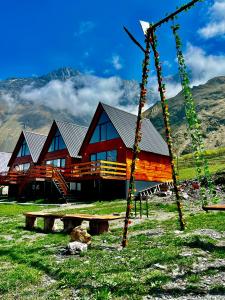 a log cabin with a swing in front of it at Cozy Home Kazbegi in Stepantsminda