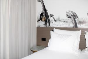 a bedroom with a bed with white sheets and a window at AP Cabanas Beach & Nature - Adults Friendly in Cabanas de Tavira