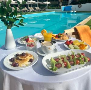 Alentejo Star Hotel - Sao Domingos - Mertola - Duna Parque Group في ميناس جي ساو دومينغو: طاولة مع أطباق من طعام الإفطار بجوار حمام سباحة