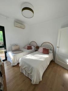 two beds in a room with white walls and wooden floors at Sunset Villa Arcos in Arcos de la Frontera