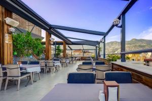 un restaurant avec des tables, des chaises et des montagnes en arrière-plan dans l'établissement ERGÜN OTEL, à Alanya