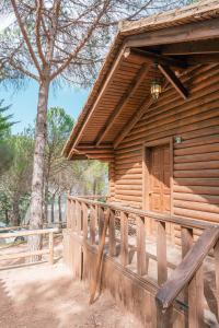 Cabaña de madera con valla de madera y árbol en Camping TajoRodillo, en Grazalema