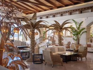 un vestíbulo con palmeras, sillas y mesas en Grecotel Marine Palace & Aqua Park, en Panormos Rethymno