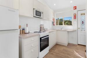 una cucina bianca con fornelli e microonde di Madigan Cottages - The Kookaburra Cottage a Lovedale