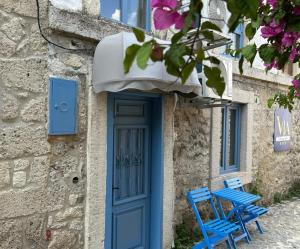 twee blauwe stoelen buiten een gebouw met een blauwe deur bij Via Alaçatı Otel in Çeşme