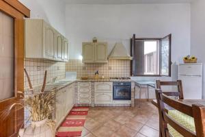 cocina con armarios blancos, mesa y fogones en Villa Cisura Ranne - 2 chilometri dal mare con piscina privata, en Diso