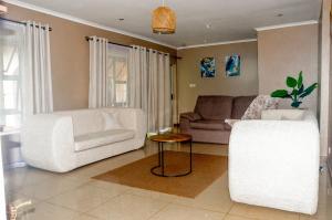 a living room with two white chairs and a couch at The47 Cozy Cottage in Lilongwe