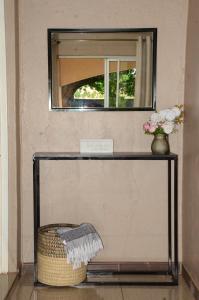 a mirror on a wall with a basket and flowers on a shelf at The47 Cozy Cottage in Lilongwe +1 photo