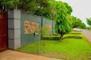 a blue brick wall with a tree next to a building at The47 Cozy Cottage in Lilongwe