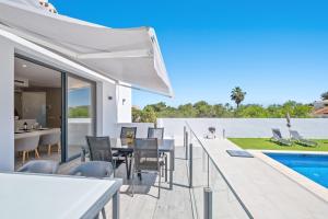 un patio al aire libre con mesa y sillas y una piscina en Amazing Villa in El Faro, en Fuengirola