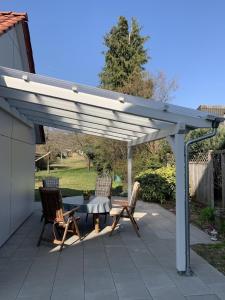 een witte pergola op een patio met 2 stoelen en een tafel bij Ferienhaus in ruhiger Lage mit großem Garten in Orsingen-Nenzingen