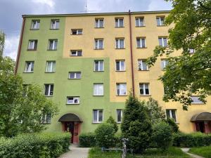 um edifício amarelo e verde com árvores em frente em Apartament P38 em Tarnów