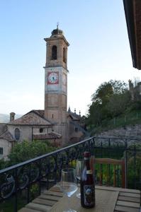 a table with a bottle of wine and a clock tower at AlbaLuna - panorama sulle Langhe in Guarene +14 photos
