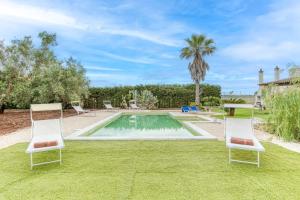 una piscina con 2 sillas de césped y una palmera en Villa Cisura Ranne - 2 chilometri dal mare con piscina privata, en Diso