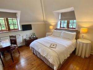 a bedroom with a large white bed and a desk at Acorn House in Cape Town