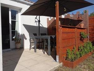 een patio met een parasol en een tafel en stoelen bij L'Escale Cotinarde in La Cotinière